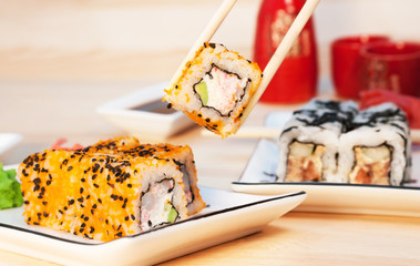 Sushi rolls on the white plate on wooden background