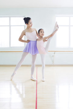 Young ballet instructor teaching girl in ballet studio