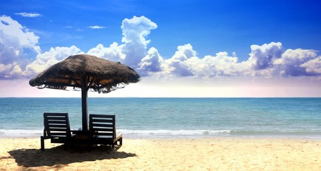 Beach chairs on the tropical sand with cloudy blue sky