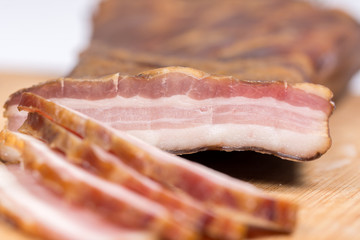 Sliced raw smoked bacon on the wooden board