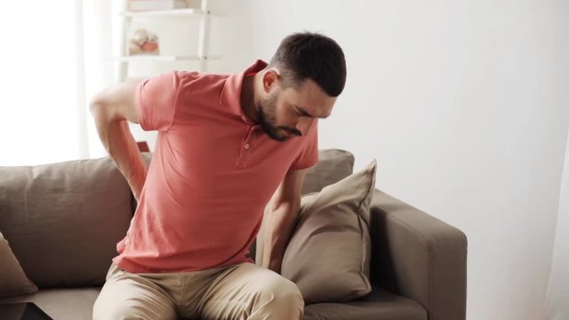 unhappy man suffering from backache at home