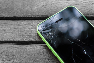 Broken screen glass of mobile smartphone on the wood table