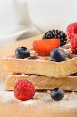 freshly baked waffles with sweet fruits and powdered sugar