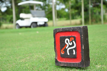 Sign at tee off with golf cart on golf course