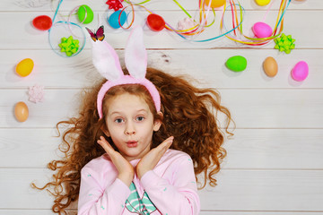 Curly girl wearing bunny ears on Easter spring holiday background.