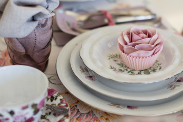 Whimsical place setting with sugar rose cupcake on vintage china. Sweet and romantic detail of tea party table. Perfect for a DIY, vintage or farm wedding.