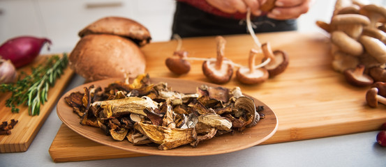 Closeup of mushrooms in a dish with woman stringing mushrooms
