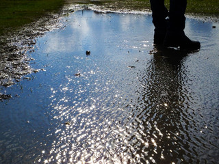 Beautiful landscape of a man's boots in puddle and sky