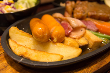 Grilled sausages vegetables in a pan grill on the table