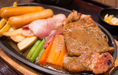 Grilled steaks with sausages vegetables in a pan grill on the ta