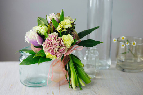 Fresh, spring wedding bouquet made with peonies in rustic glass jar. Pastel color palette.