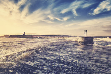 Retro stylized sunset over port entrance, Ustka, Poland.