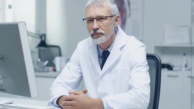 Experienced Gray Haired Senior Medical Practitioner Looking Into Camera. Portrait Shot in Modern and Light Office.  Shot on RED Cinema Camera in 4K (UHD). 