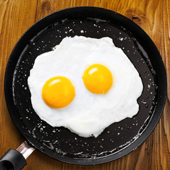 Traditional healthy easy quick breakfast meal made of two fried eggs served on a frying pan. International simple food, top view.