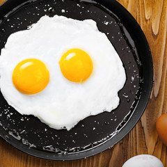 Fried eggs for delicious healthy easy breakfast on a table. Fresh homemade meal on a frying pan. Traditional breakfast food. International cuisine food.  Top view.