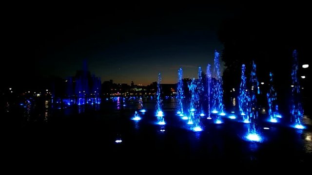 Colorfully lit fountain in a park at night