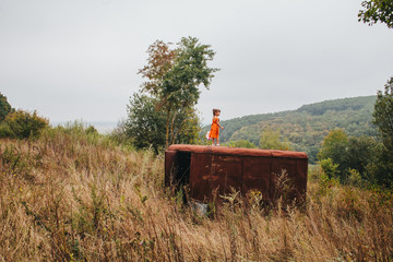 Naklejka premium little girl stands on the old trailer in the woods