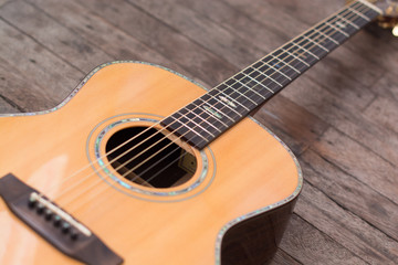 Obraz premium Acoustic guitar resting against a wooden background with copy sp