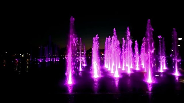 Colorfully lit fountain in a park at night