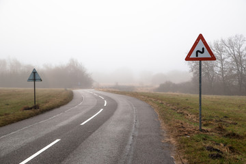 foggy road with warning sign