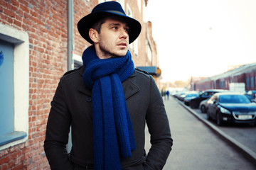 Trendy handsome young man in autumn fashion standing in urban environment.