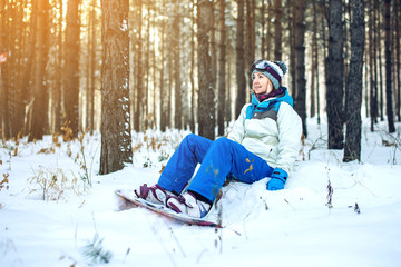 Fototapeta na wymiar woman snowboarder with snowboard is resting sitting on the snow