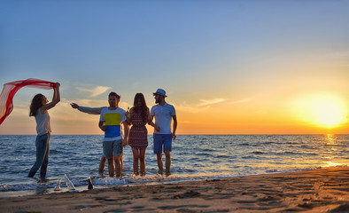 Fototapeta premium group of happy young people dancing at the beach on beautiful summer sunset