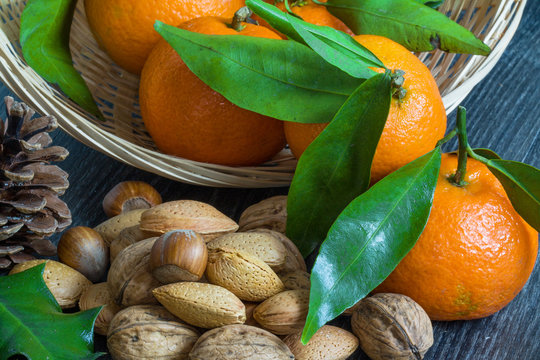 Cl&eacute;mentines corses et leurs feuilles avec amandes, noix et noisettes  sur fond noir