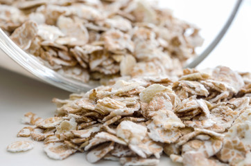 Pile of the uncooked raw oat flakes near glass bowl. Healthy lifestyle concept. Closeup macro shot.