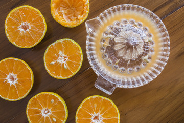 Oranges cut with manual glass squeezer on wooden table