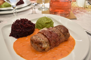 Pork steak filled with cheese wrapped in bacon with red cabbage and smashed peas