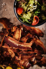 Top view of fried bacon and salad standing on table