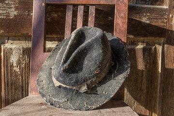 Battered old hat damaged by clothes moth on vintage background. A forgotten hat covered with spider web among the ruins of a house. Imagine the owner of this hat and tell their story.