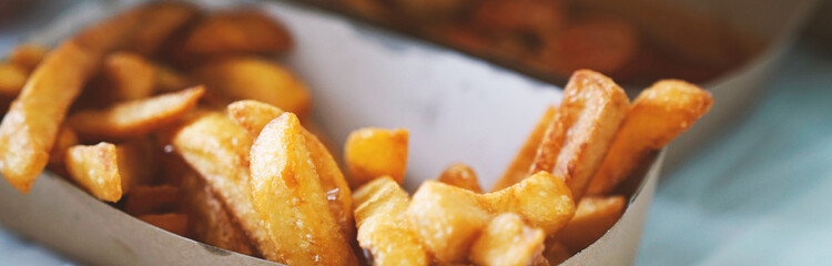 French fries on tracing paper on board on wooden table