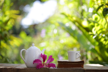white tea pot and mug with flower and notebook on wooden table