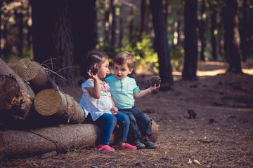 Girl and boy sitting at log