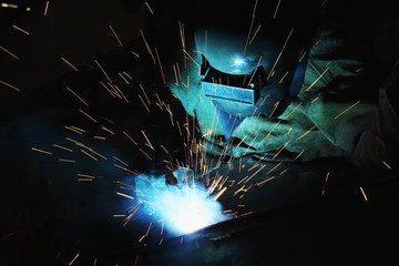 Welder of Metal Welding with sparks and smoke in manufacturing