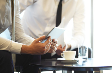 Close-up of a modern business team using tablet computer to work with financial data.