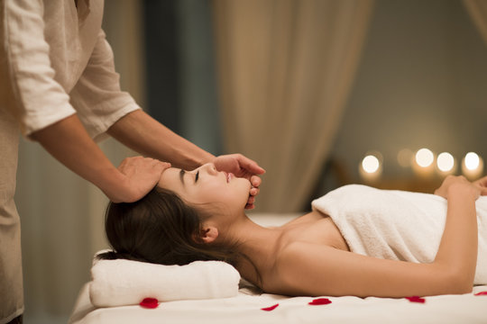 Masseuse giving a facial massage to a woman in a spa