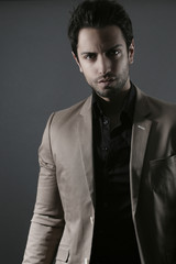 jeune homme élégant habillé d' une veste de costume marron.