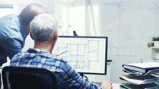 Two Senior Architectural Engineers Working With Building Plan on a Personal Computer. They Actively Discuss Various Plans and Schemes.  Shot on RED Cinema Camera in 4K (UHD). 