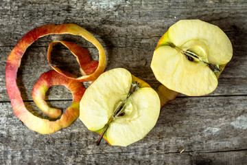 Two apple halves with peeled peel on wooden table, top view