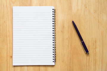 Blank paper note book with pen on wood table background