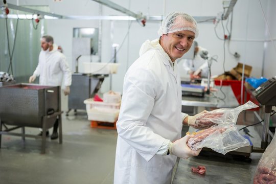 Butcher weighing packages of meat - Powered by Adobe