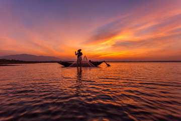 Silhouette of traditional fishermen throwing net fishing inle lake at sunrise time, Myanmar
