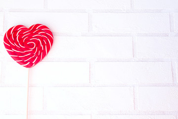Lollipop heart on vintage white brick wall background. Empty space for your text. Valentine day postcard.