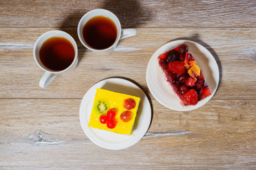 Two cups with tea and two fruits cakes on the wooden table. Overhead view.
