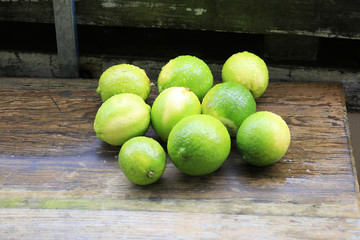 green and yellow juicy lemons and limes in a rustic interior lay on a wooden table as a still life