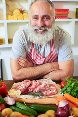 Close-up of cheerful chef in apron leaning on the table