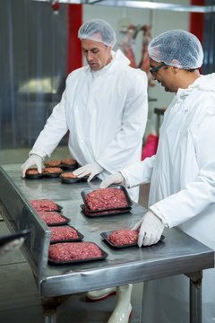 Two butchers packaging minced meat